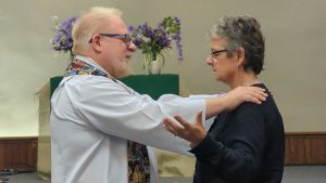 Pastor Emeritus Doug Sewell ordaining Deacon Kim Phipps as pastor on Aug 6, 2023.